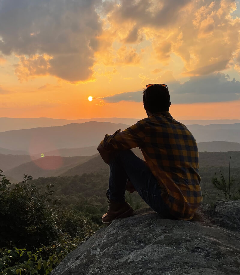 Man overlooking mountain view of sunset.