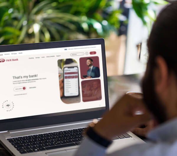 Man using a laptop with F&M Bank website on screen.