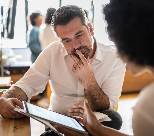Mature man looking at a digital tablet that a colleague is showing at work