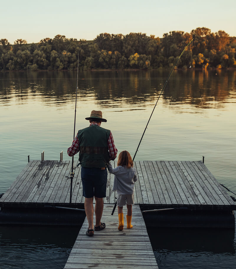 Grandfather and granddaughter fishing on dock.