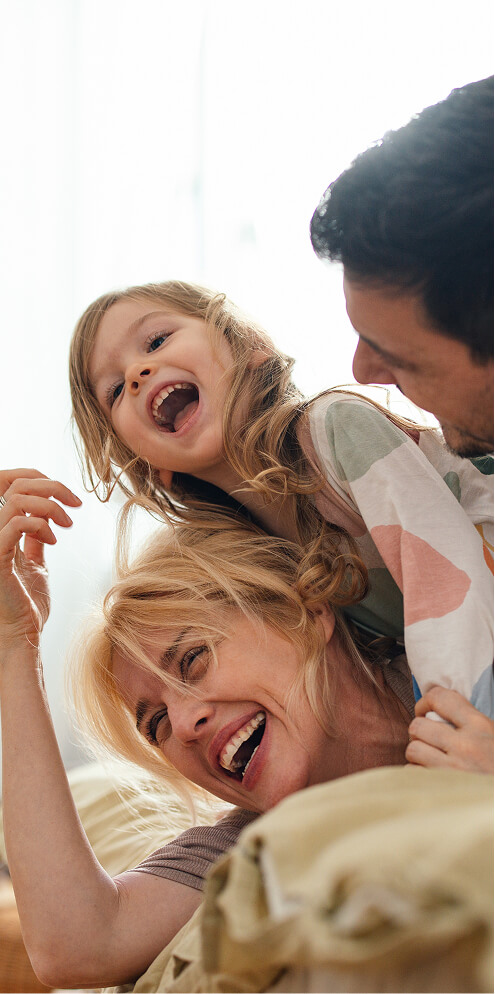 Family laughing on bed.