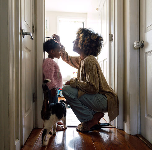 Mother and daughter checking height on door frame.