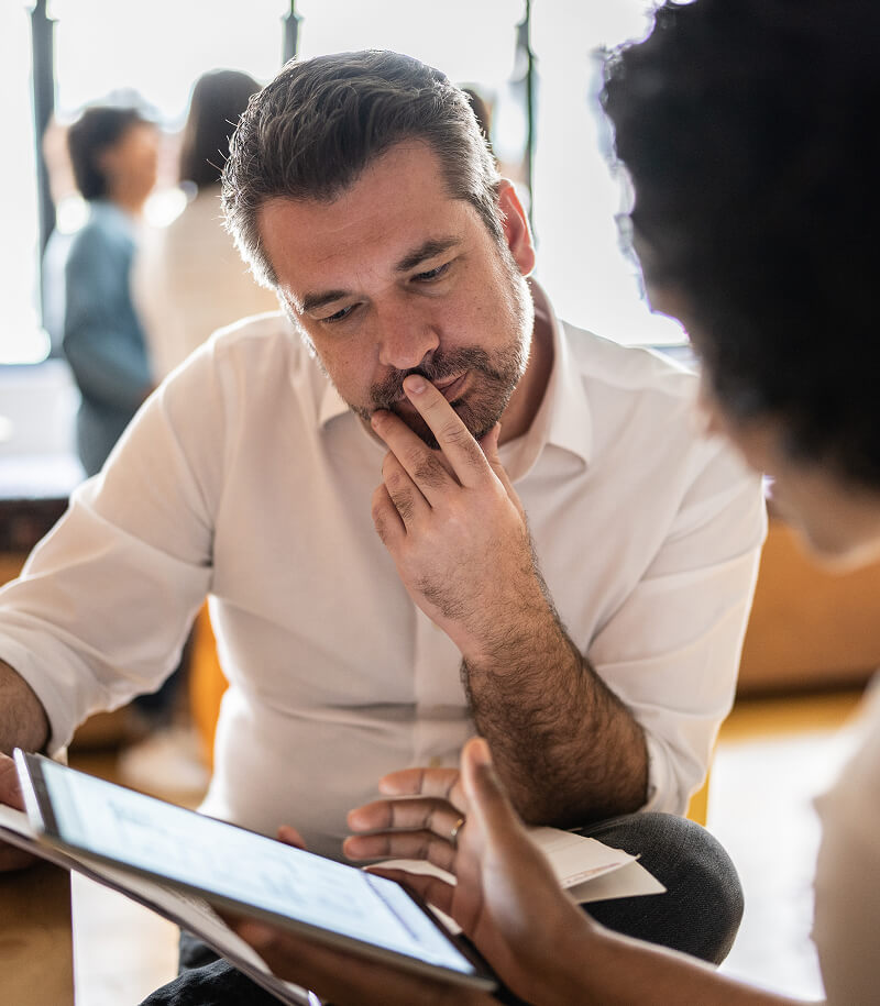 Mature man looking at a digital tablet that a colleague is showing at work