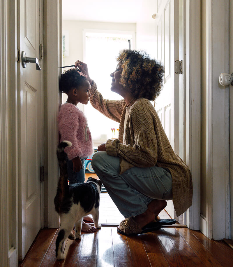 Mother and daughter checking height on door frame.