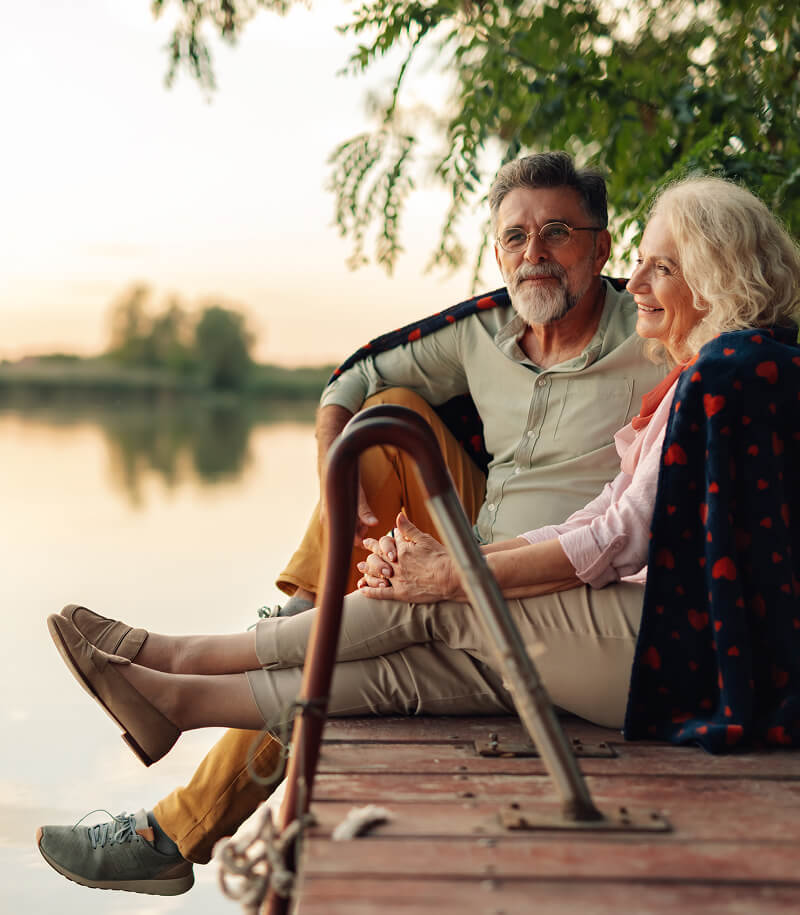 Mature couple sitting on lake dock.