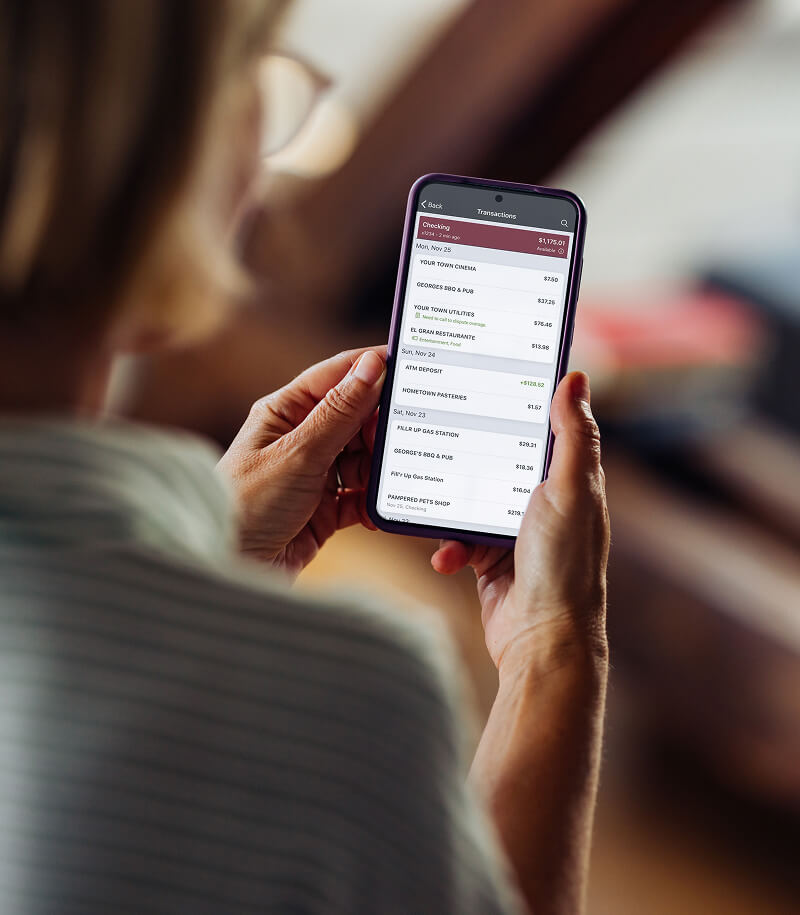 Woman managing account details in F&M Bank mobile banking app on smartphone.