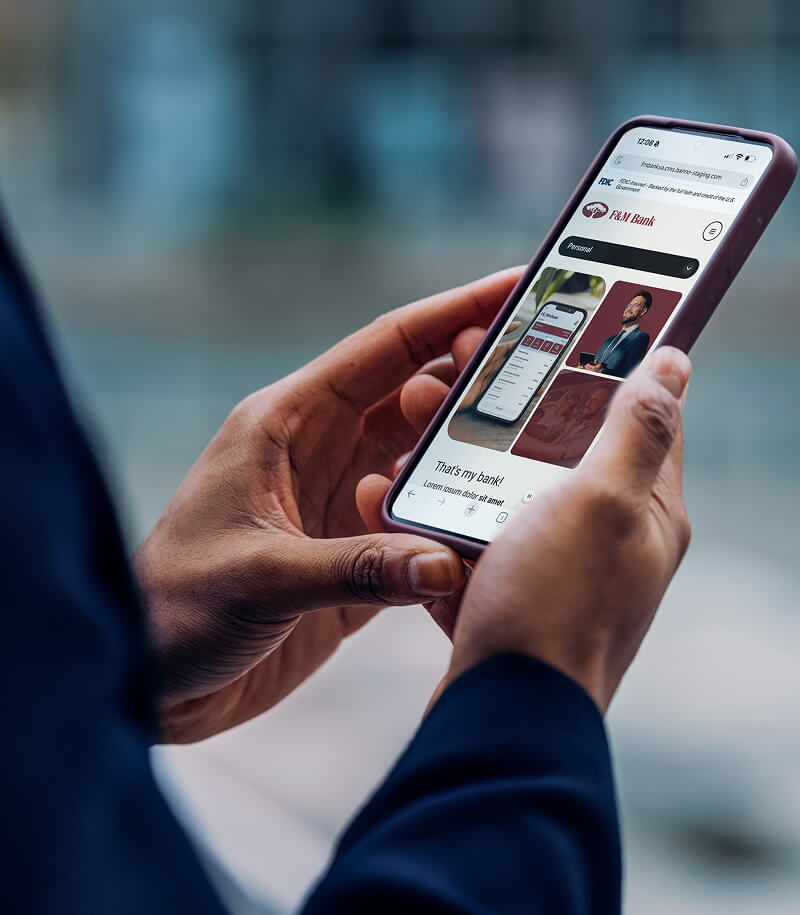 Business person with F&M Bank website on mobile device.