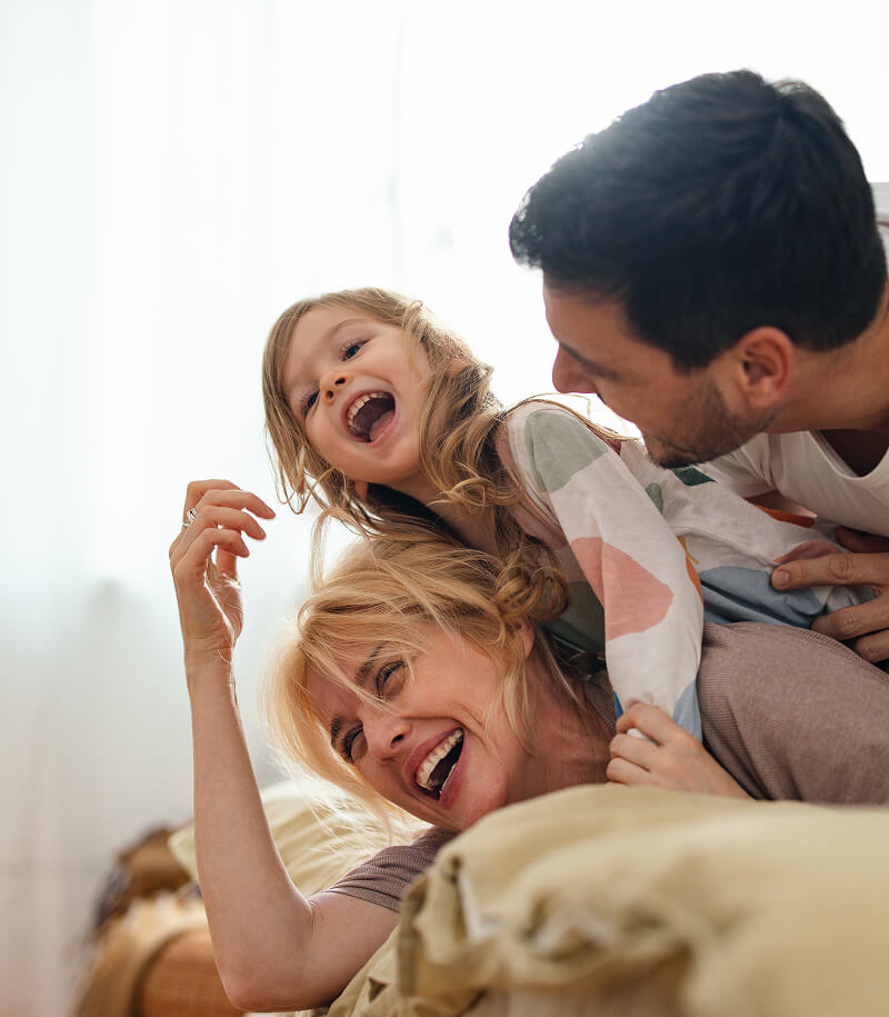 Family laughing on bed.