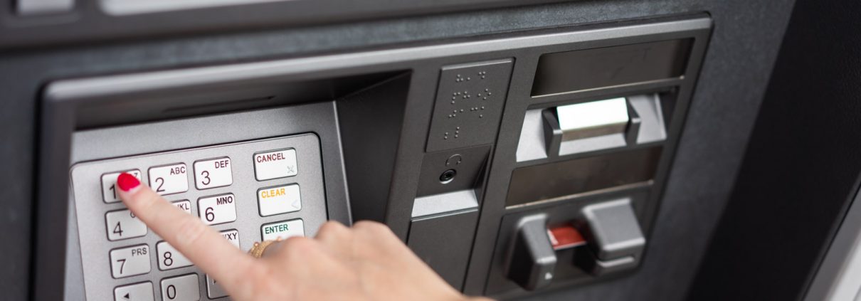 A customer's hand inserting a debit card into an ATM machine