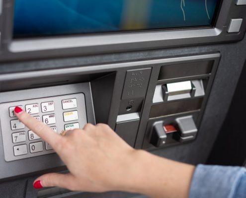 A customer's hand inserting a debit card into an ATM machine