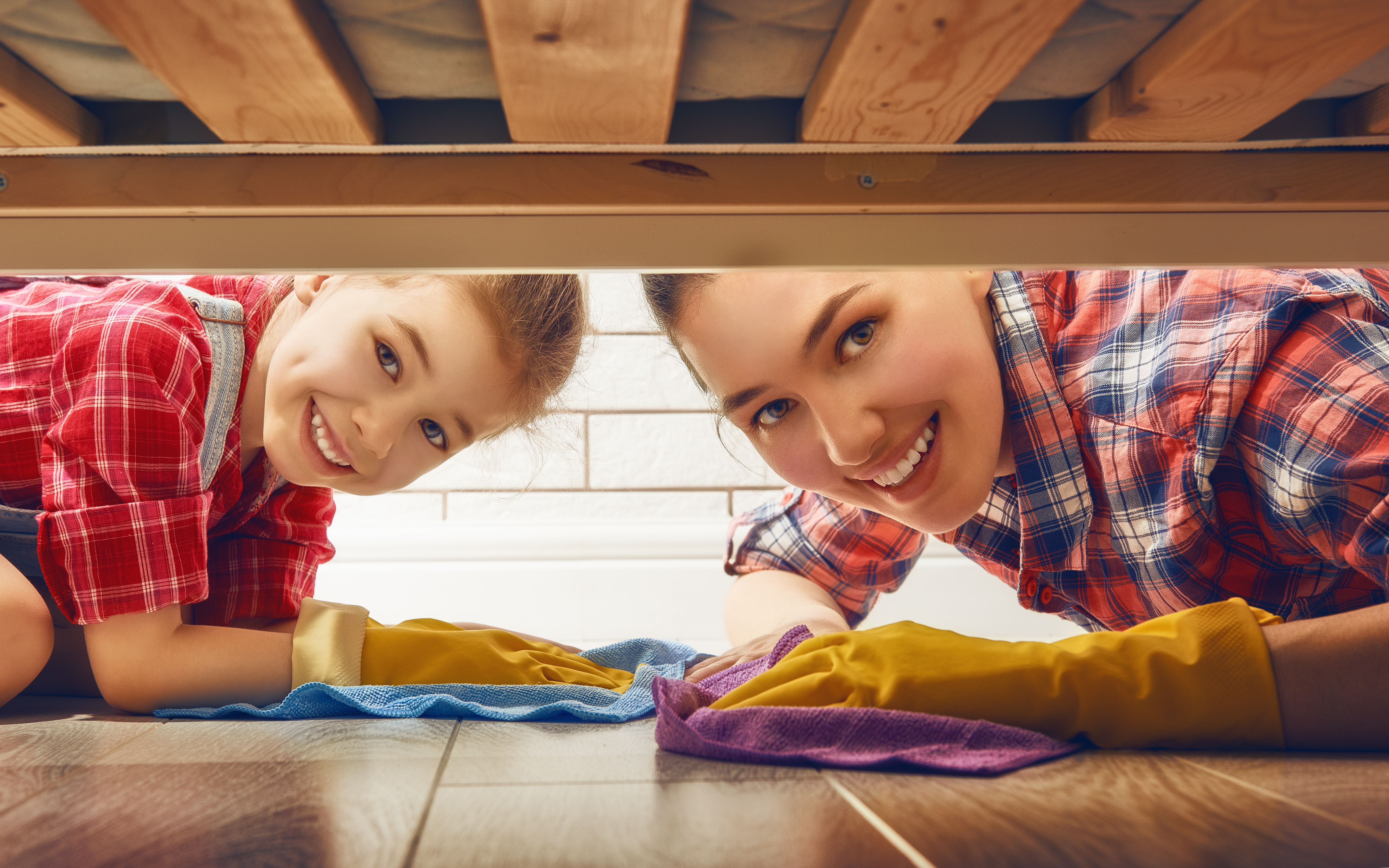 Image of woman and child peeking under a bed while cleaning