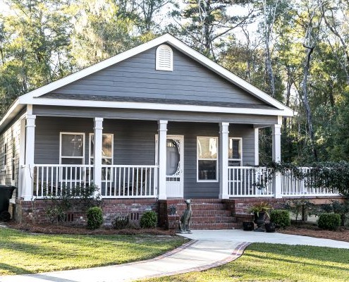 Image of home with front porch and brick steps. Trees behind the house.