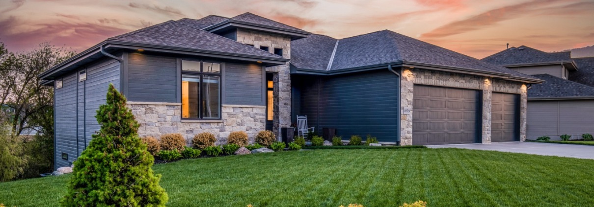 Home in center with sunset behind it and yard in front