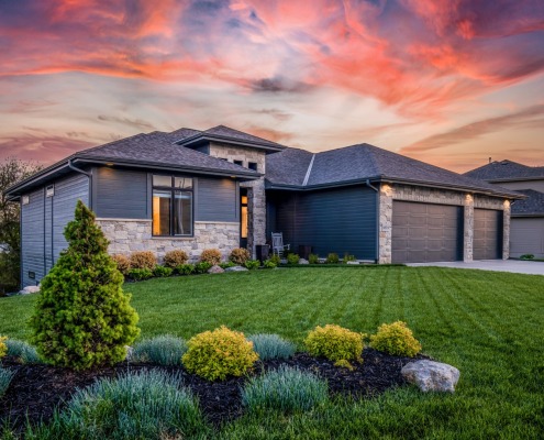 Home in center with sunset behind it and yard in front